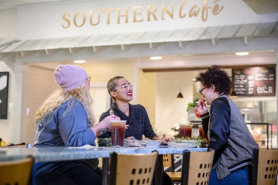 several students laugh and enjoy fresh salads and tea at the Southern Cafe